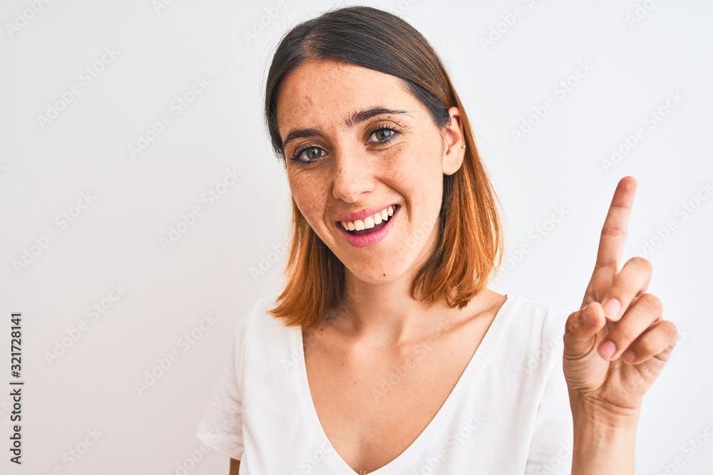 Beautiful redhead woman wearing casual white t-shirt over isolated background surprised with an idea or question pointing finger with happy face, number one Beautiful redhead woman wearing casual white t-shirt over isolated background surprised with an idea or question pointing finger with happy face, number one