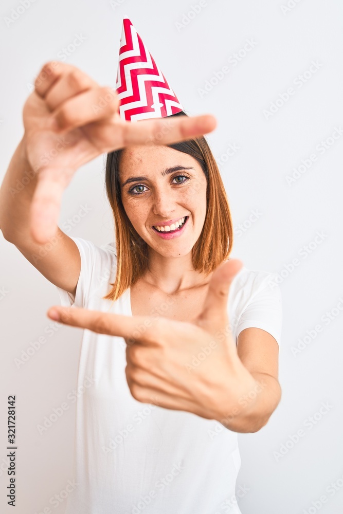 Beautiful redhead woman wearing birthday cap over isolated background smiling making frame with hands and fingers with happy face. Creativity and photography concept. Beautiful redhead woman wearing birthday cap over isolated background smiling making frame with hands and fingers with happy face. Creativity and photography concept.