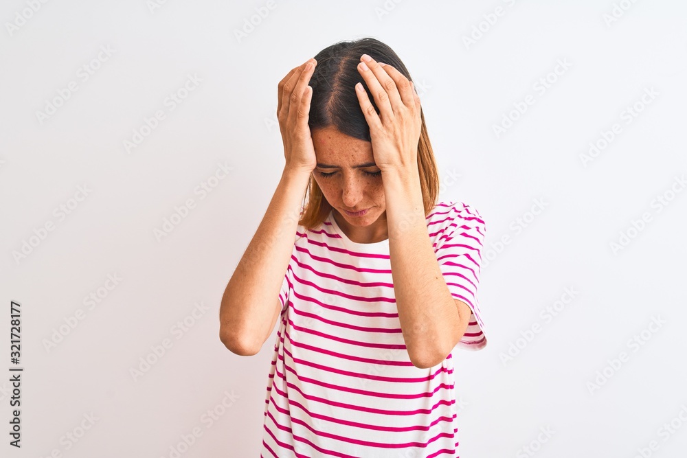 Beautiful redhead woman wearing casual striped pink t-shirt over isolated background suffering from headache desperate and stressed because pain and migraine. Hands on head. Beautiful redhead woman wearing casual striped pink t-shirt over isolated background suffering from headache desperate and stressed because pain and migraine. Hands on head.