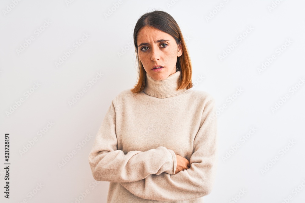 Beautiful redhead woman wearing winter turtleneck sweater over isolated background skeptic and nervous, disapproving expression on face with crossed arms. Negative person.