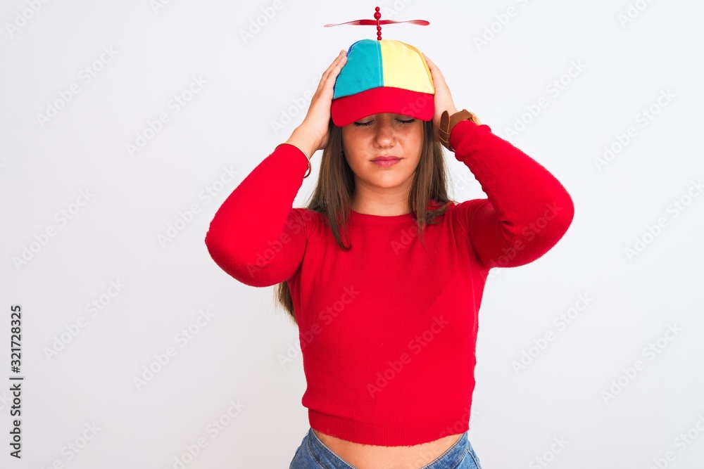 Young beautiful girl wearing fanny cap with propeller standing over isolated white background suffering from headache desperate and stressed because pain and migraine. Hands on head. Young beautiful girl wearing fanny cap with propeller standing over isolated white background suffering from headache desperate and stressed because pain and migraine. Hands on head.