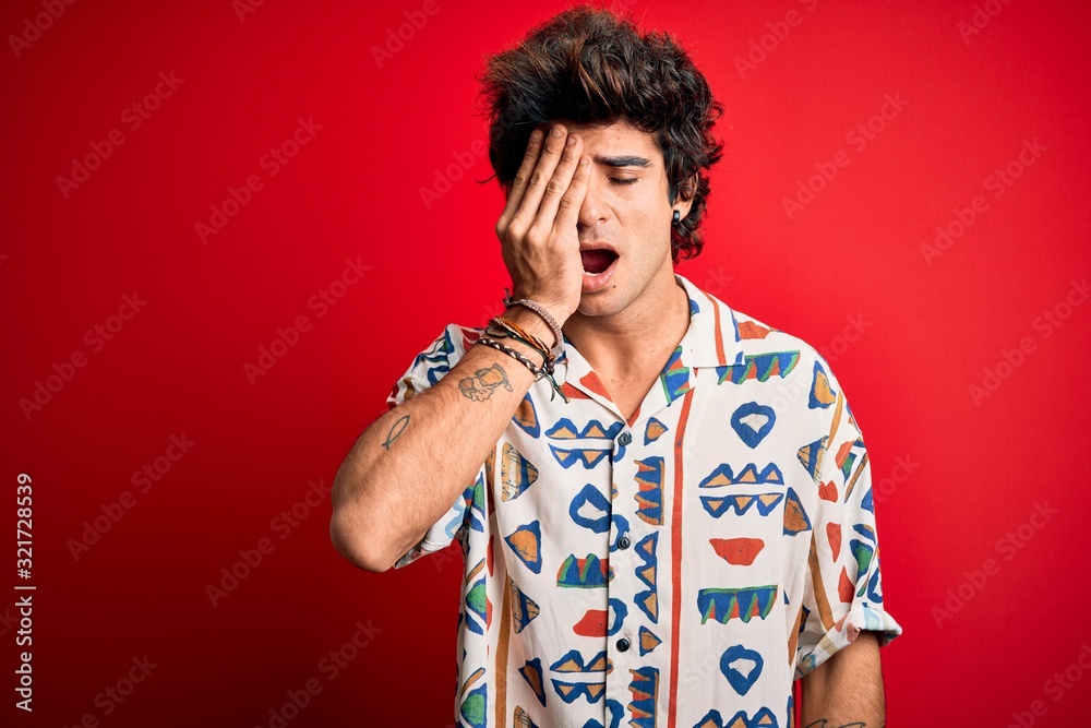 Young handsome man on vacation wearing summer shirt over isolated red background Yawning tired covering half face, eye and mouth with hand. Face hurts in pain. Young handsome man on vacation wearing summer shirt over isolated red background Yawning tired covering half face, eye and mouth with hand. Face hurts in pain.