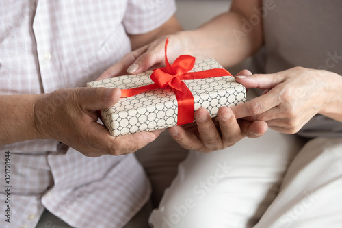 Elderly loving wife greeting husband with gift box