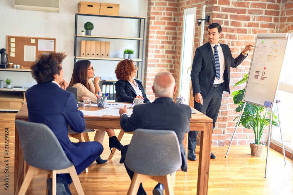 Group of business workers smiling happy and confident in a meeting. Working together looking at presentation using board and charts at the office.