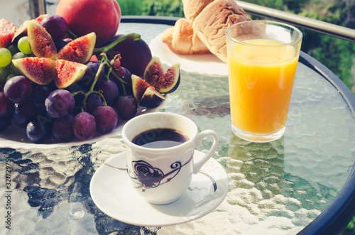 Breakfast table with coffee, orange juice, fruits and croissants