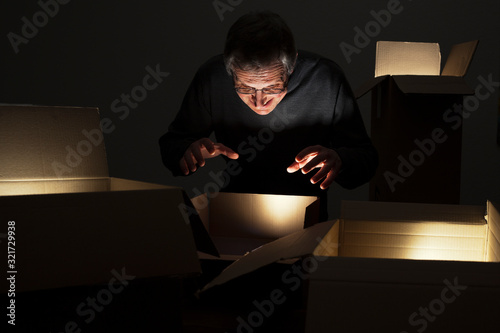 Tableau sur toile Mature greedy man opening parcels with ligthts inside