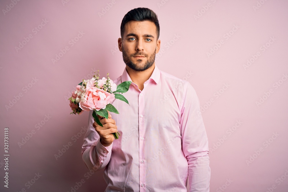 Young romatic man holding bouquet of spring flowers over pink isolatd background with a confident expression on smart face thinking serious Young romatic man holding bouquet of spring flowers over pink isolatd background with a confident expression on smart face thinking serious