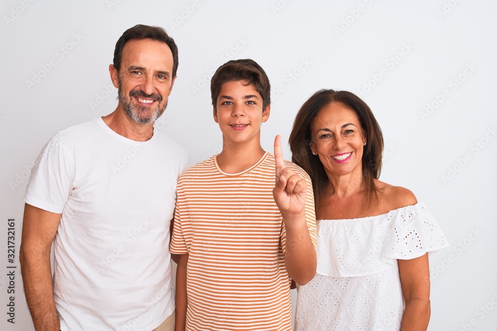 Obraz premium Family of three, mother, father and son standing over white isolated background showing and pointing up with finger number one while smiling confident and happy.