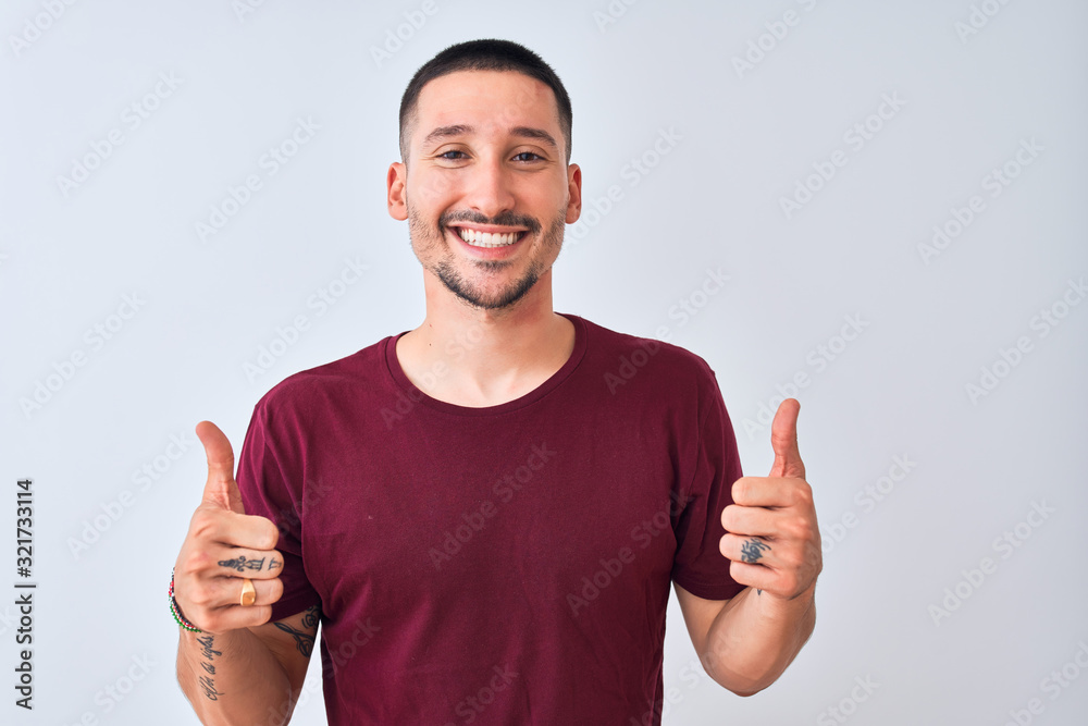 Young handsome man standing over isolated background success sign doing positive gesture with hand, thumbs up smiling and happy. Cheerful expression and winner gesture. Young handsome man standing over isolated background success sign doing positive gesture with hand, thumbs up smiling and happy. Cheerful expression and winner gesture.