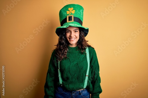 Canvas Print Beautiful curly hair woman wearing green hat with clover celebrating saint patricks day with a happy and cool smile on face