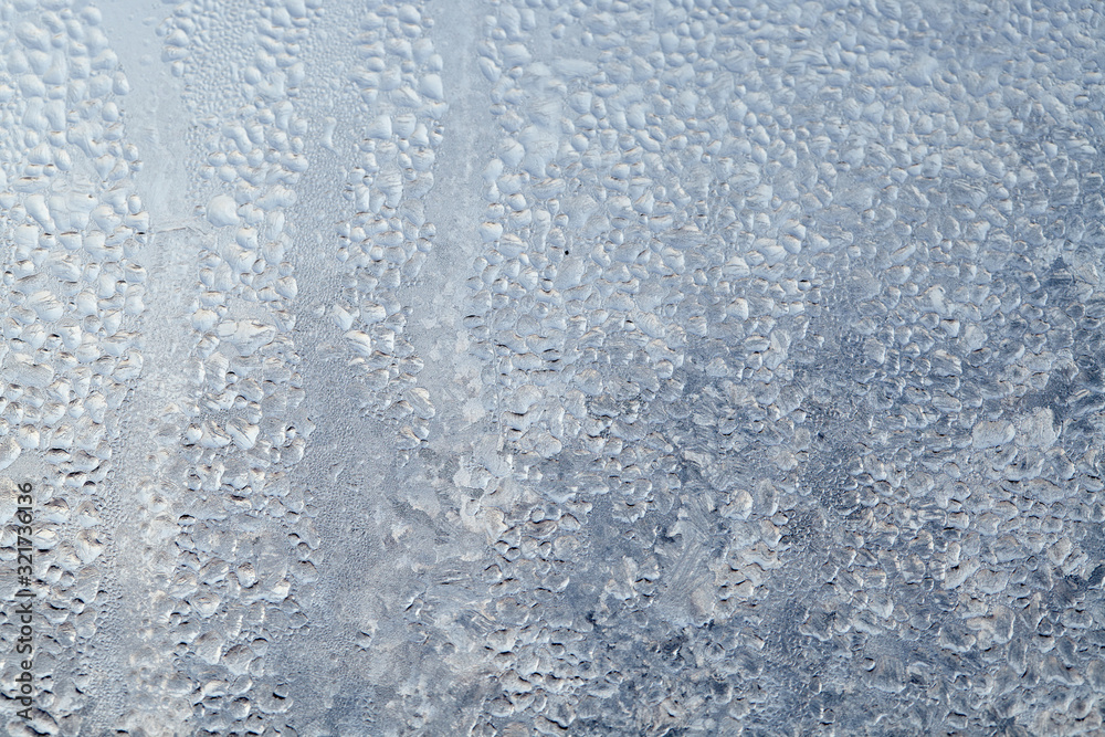 Obraz premium Frozen drops of condensed steam water drops on the transparent window glass. Clean background. Condensation of moisture at extreme temperatures. Water vapor condenses on cold window glass and freezes