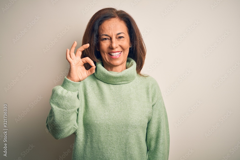 Middle age beautiful woman wearing casual turtleneck sweater over isolated white background smiling positive doing ok sign with hand and fingers. Successful expression. Middle age beautiful woman wearing casual turtleneck sweater over isolated white background smiling positive doing ok sign with hand and fingers. Successful expression.