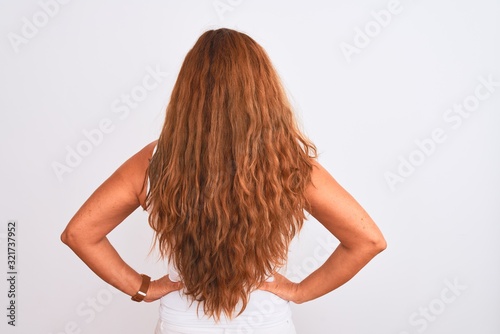 Middle age mature woman standing over white isolated background standing backwards looking away with arms on body