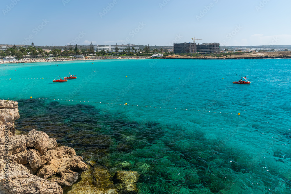 CYPRUS, NISSI BEACH - MAY 12/2018: Tourists swim on catamarans and kayaks in the popular bay of the Mediterranean Sea.