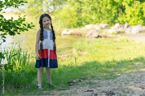 Portrait of a beautiful little girl with long hair on a background of nature on a sunny day.