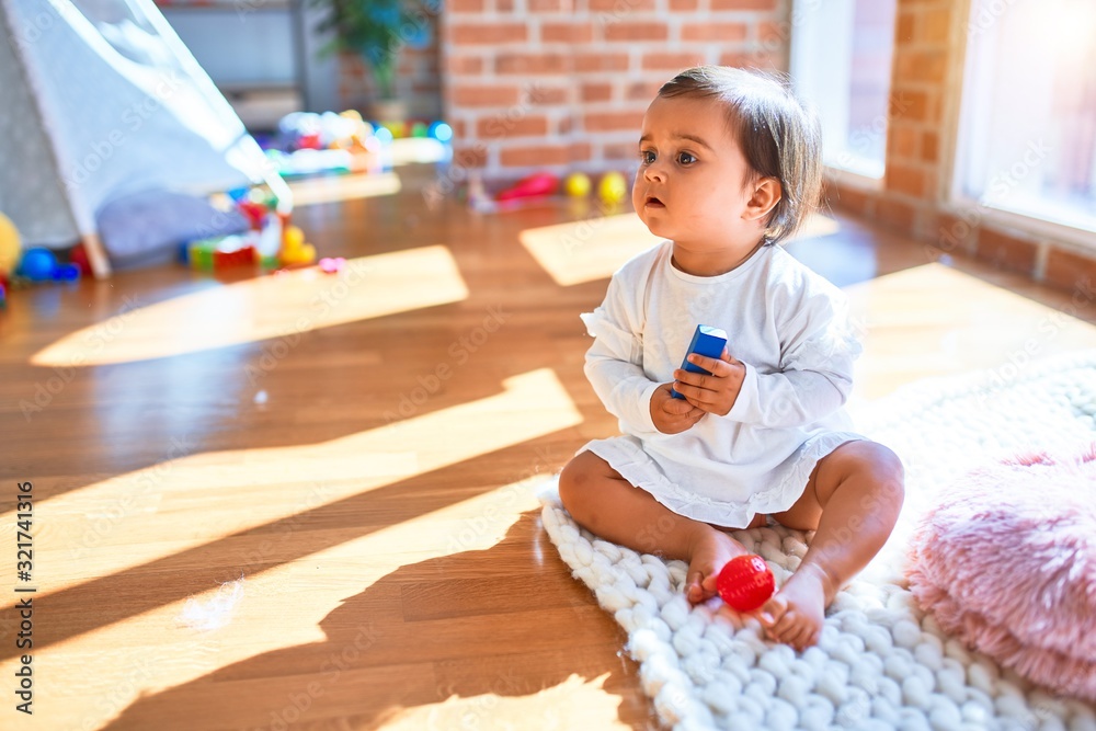 Beautiful infant happy at kindergarten around colorful toys Beautiful infant happy at kindergarten around colorful toys