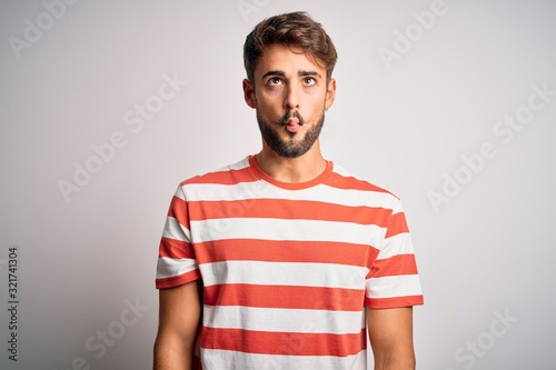 Wallpaper Mural Young handsome man with beard wearing striped t-shirt standing over white background making fish face with lips, crazy and comical gesture. Funny expression. Torontodigital.ca