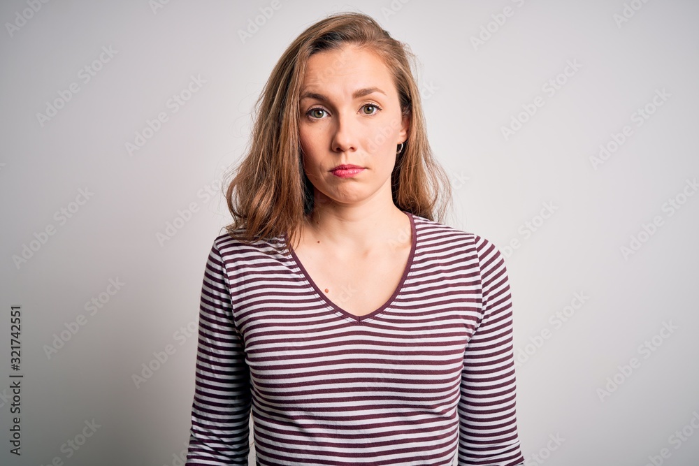 Young beautiful blonde woman wearing casual striped t-shirt over isolated white background with serious expression on face. Simple and natural looking at the camera.