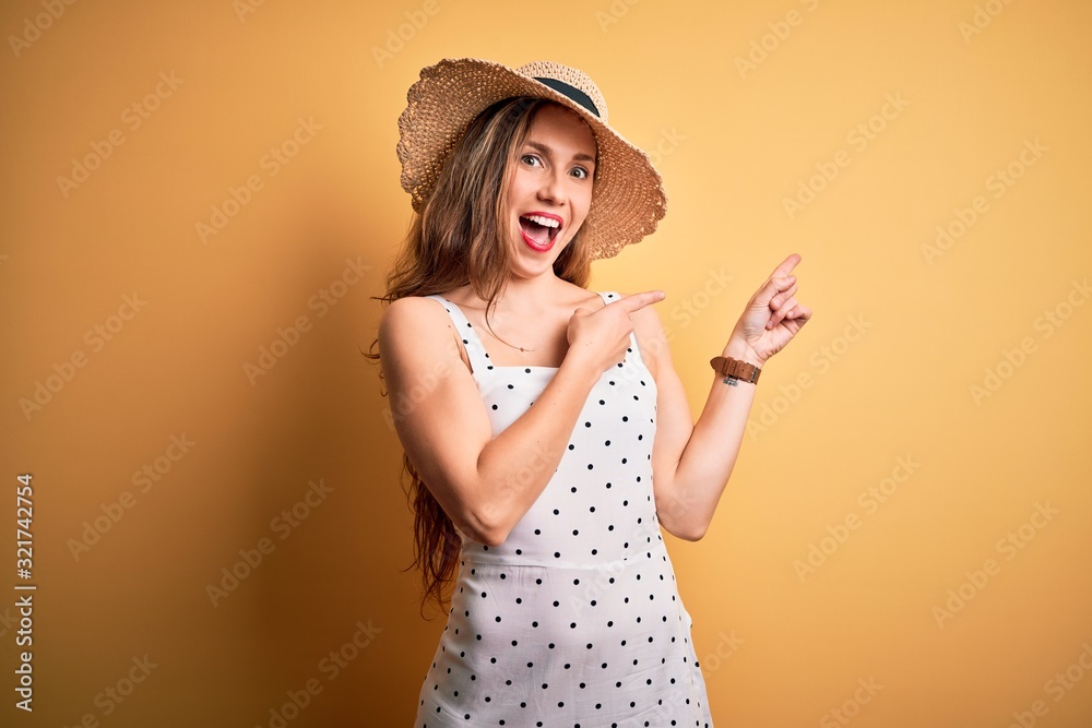 Young beautiful blonde woman on vacation wearing summer hat over yellow background smiling and looking at the camera pointing with two hands and fingers to the side. Young beautiful blonde woman on vacation wearing summer hat over yellow background smiling and looking at the camera pointing with two hands and fingers to the side.