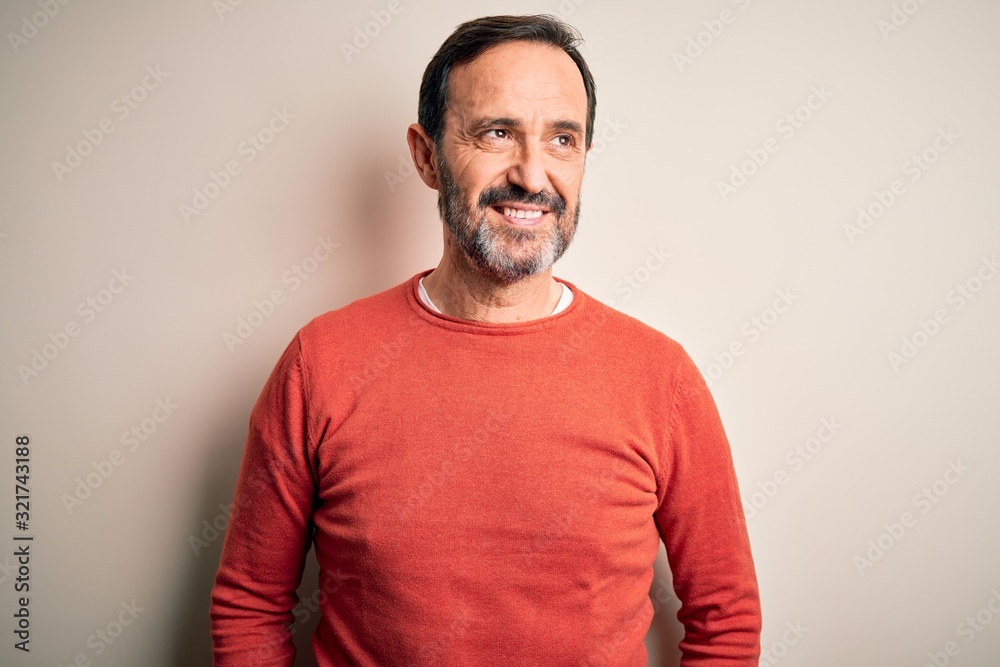 Middle age hoary man wearing casual orange sweater standing over isolated white background smiling looking to the side and staring away thinking. Middle age hoary man wearing casual orange sweater standing over isolated white background smiling looking to the side and staring away thinking.