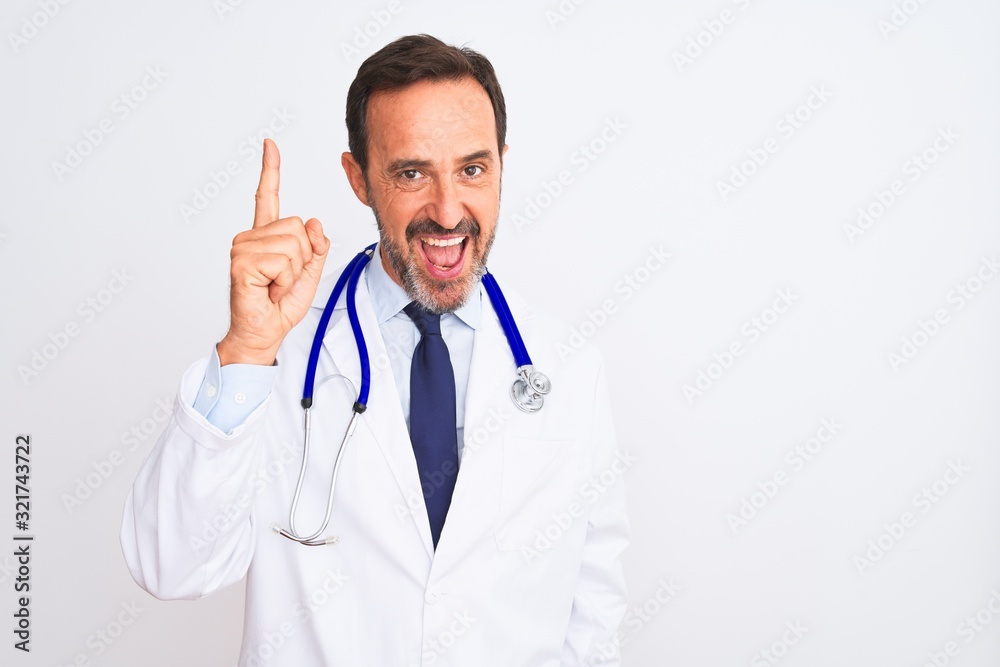 Middle age doctor man wearing coat and stethoscope standing over isolated white background pointing finger up with successful idea. Exited and happy. Number one. Middle age doctor man wearing coat and stethoscope standing over isolated white background pointing finger up with successful idea. Exited and happy. Number one.