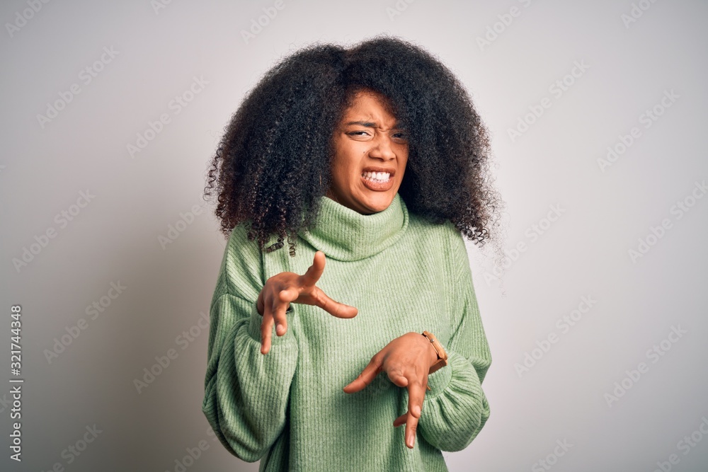 Young beautiful african american woman with afro hair wearing green winter sweater disgusted expression, displeased and fearful doing disgust face because aversion reaction. With hands raised Young beautiful african american woman with afro hair wearing green winter sweater disgusted expression, displeased and fearful doing disgust face because aversion reaction. With hands raised