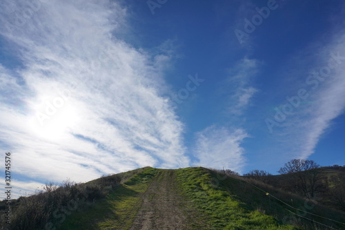 hiking trail green grass white clouds