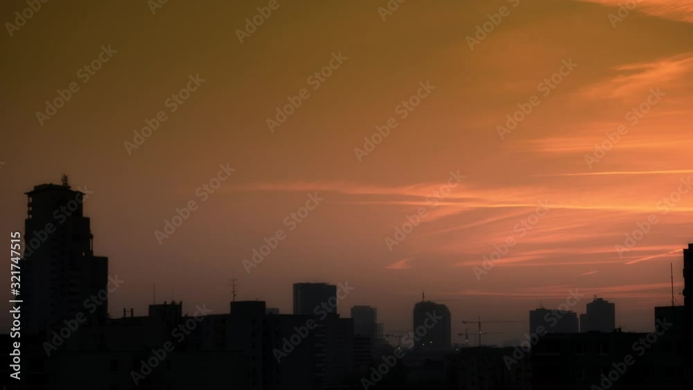 Aerial shot (Time Lapse 4K) of city silhouette from dusk to night with flying clouds and sky color changes. In the background working cranes and skyscraper building in the process of construction. Aerial shot (Time Lapse 4K) of city silhouette from dusk to night with flying clouds and sky color changes. In the background working cranes and skyscraper building in the process of construction.