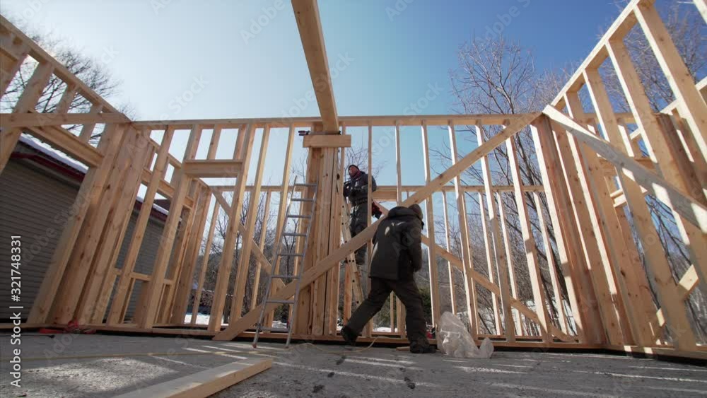 Timelapse of two framers adjusting beams with hydraylic hammer at frame house building. Sunny day