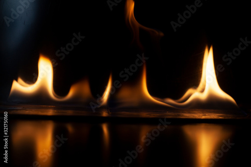 Fiery background. Flames of fire in the dark. Flame texture. Tongues of fire rise smoothly. A simple background of yellow shades. Burning gel for ignition. Ignition of vapors. Fire is danger.