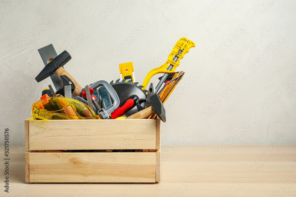 Crate with different carpenter's tools on wooden table. Space for text Crate with different carpenter's tools on wooden table. Space for text