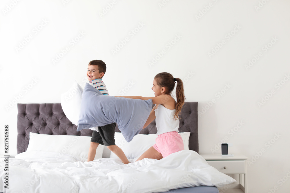 Fototapeta premium Happy children having pillow fight in bedroom
