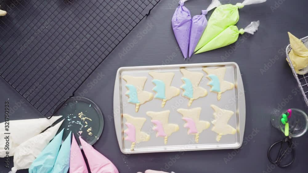 Flat lay. Decorating unicorn sugar cookies with multi-color royal icing.