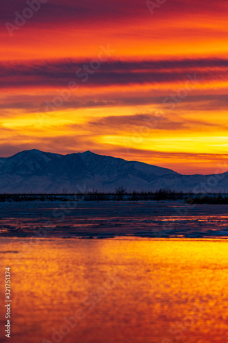 Sunrise or sunset landscape over a river with ice floating in it