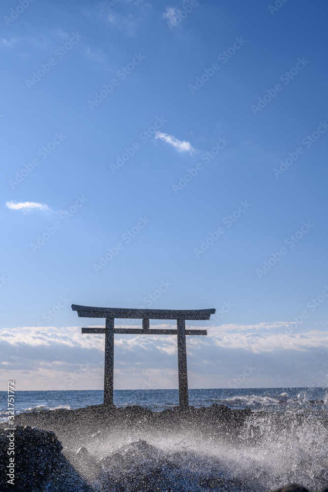 Oarai Japanese white shinto torii gate in the sea with wave splash