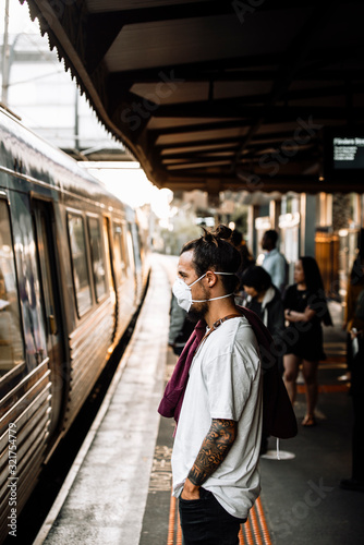 A young caucasian male waiting for the train and wearing a mask © Alex Bascuas