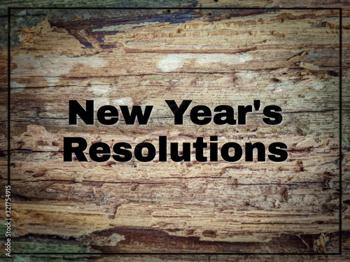 inspirational text of new year's resolutions on wood surface with vintage background