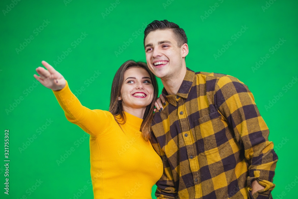 Portrait of happy couple looking and pointing into the distance, isolated on green background. Portrait of happy couple looking and pointing into the distance, isolated on green background.
