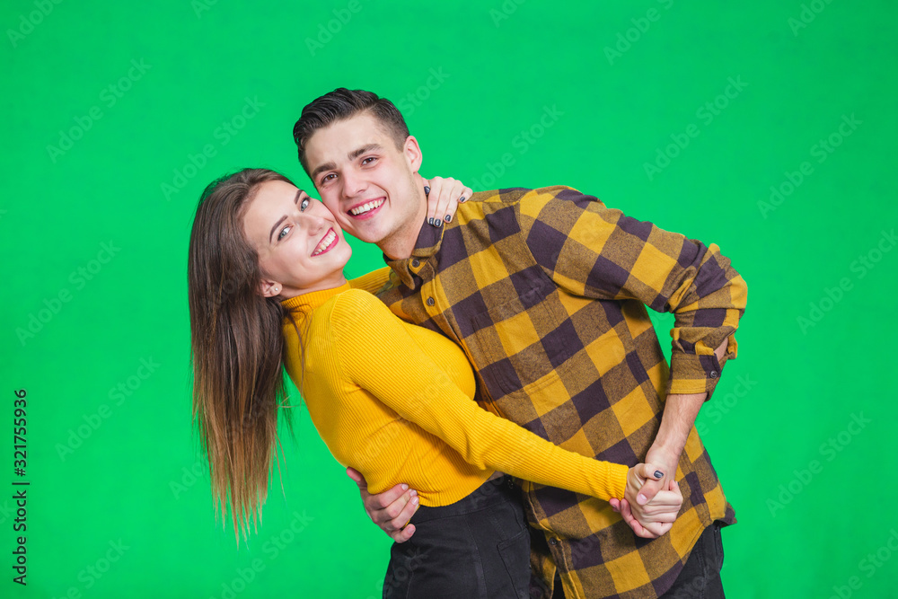 Young beautiful couple in love, dancing on green background, celebrating some special occasion. Young beautiful couple in love, dancing on green background, celebrating some special occasion.