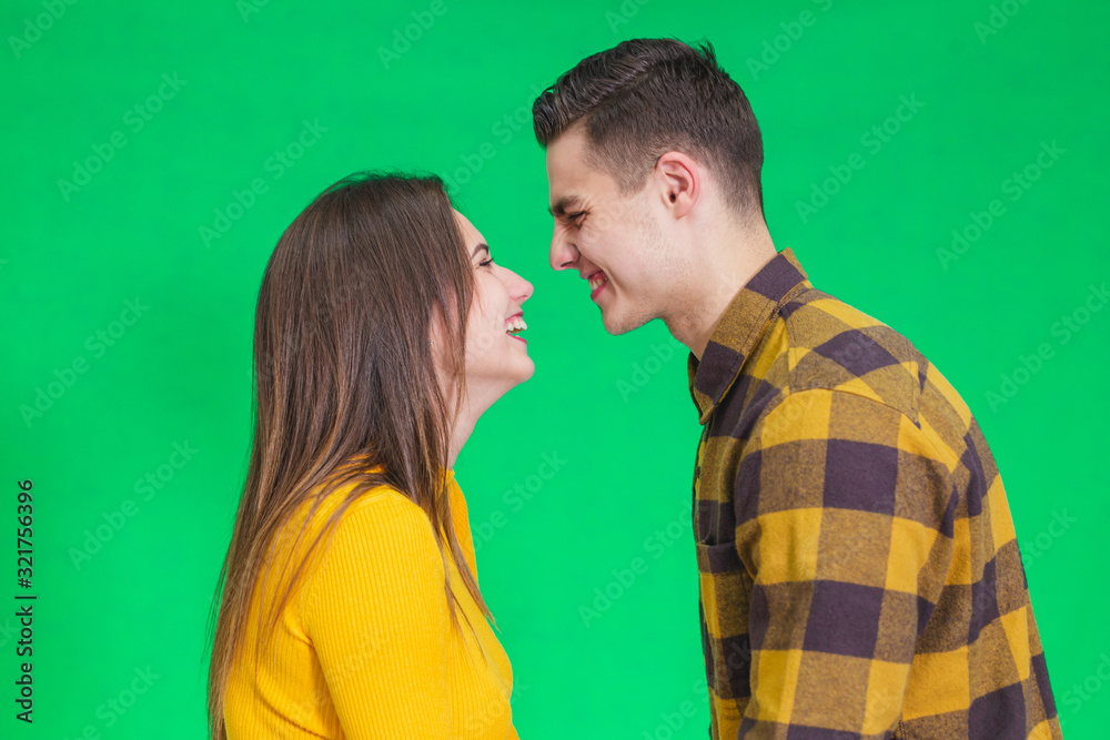 Happy calm man and woman enjoying peace of mind and kissing against green background. Happy calm man and woman enjoying peace of mind and kissing against green background.