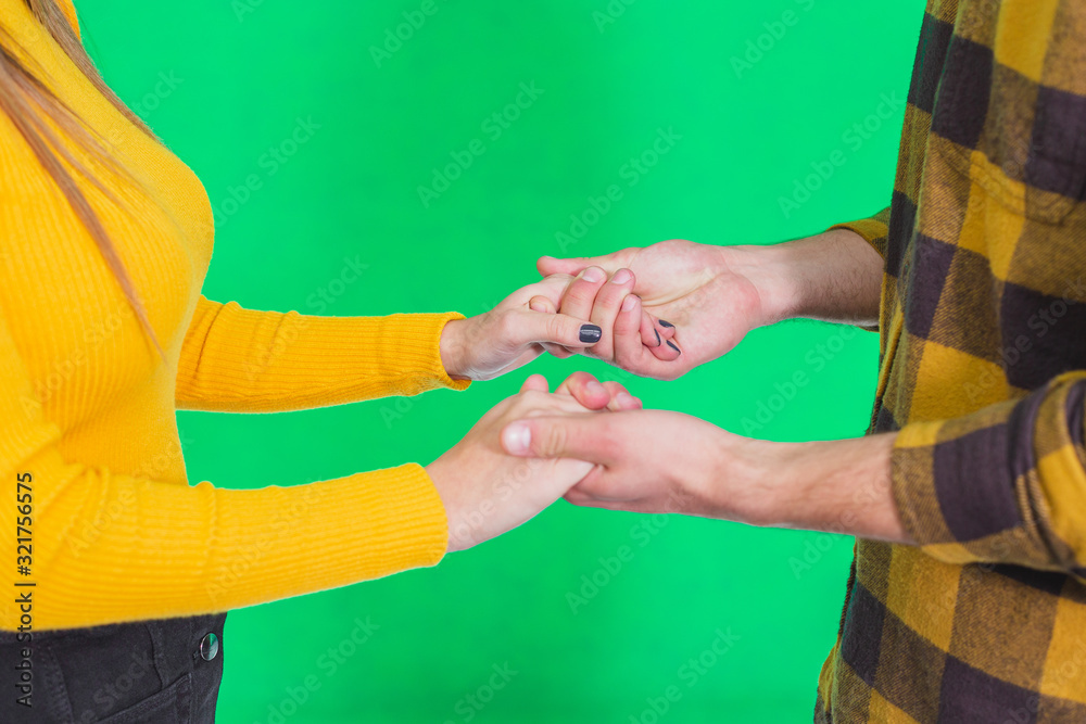 Cropped shot of hands in hands together over green background.