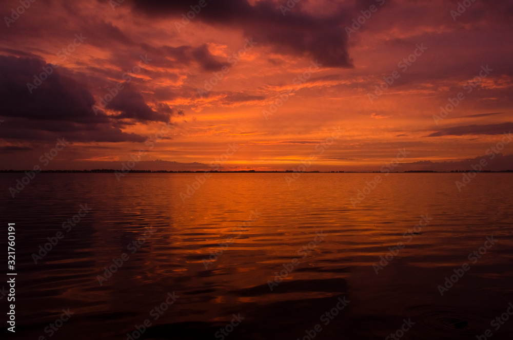 Sunset over Lake Chascomus, orange beautiful sky reflected in the water surface