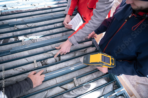 team of mining  workers measuring drilled rock core