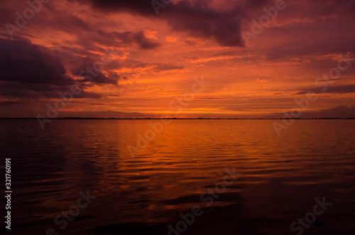 Sunset over Lake Chascomus, orange beautiful sky reflected in the water surface