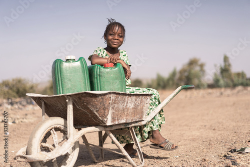 Joyful African Young Woman Transporting Natural Water for lack of water symbol