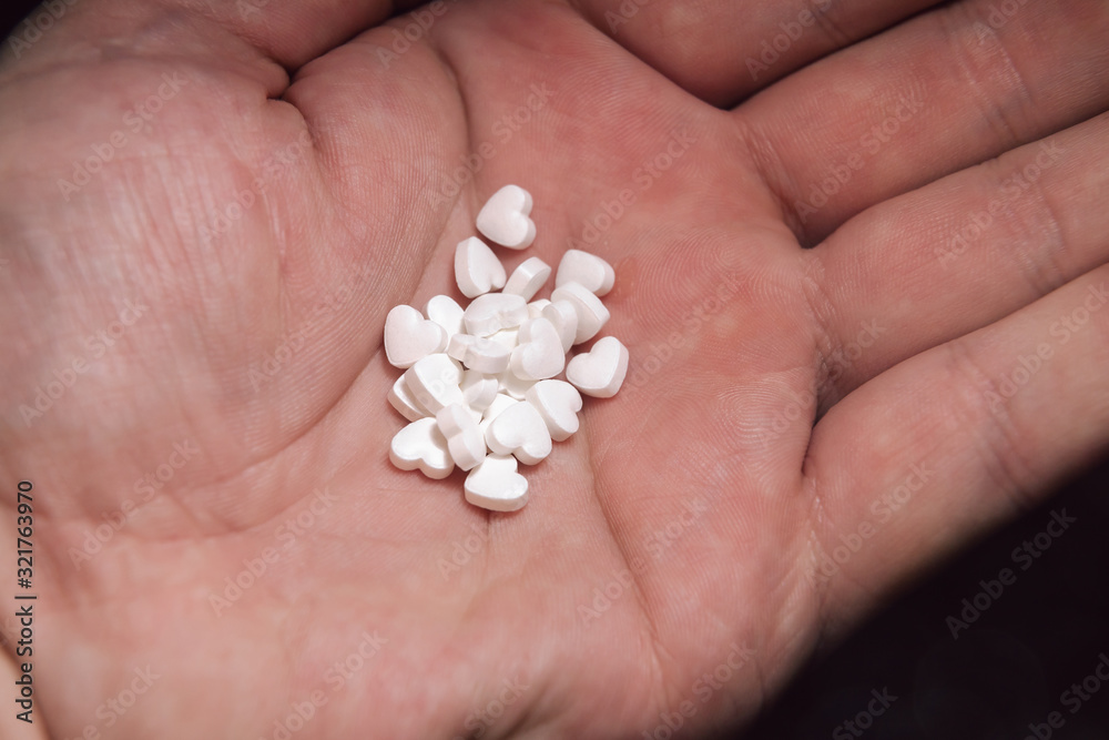 A lot of tiny white hearts on the palm. Heart-shaped pills.