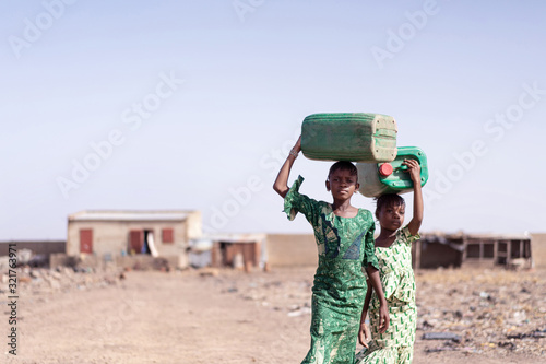 Working African Ethnicity Schoolgirl Collecting Fresh Water for lack of water symbol photo