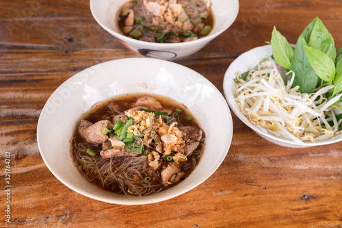 Thai Noodles "Kuay Tiew Reua" with pork and vegetables om wooden table