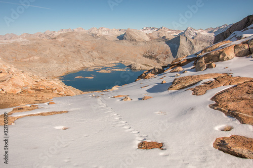animal prints in fresh snow leading to mountain lake surrounded by rocky mountain peaks