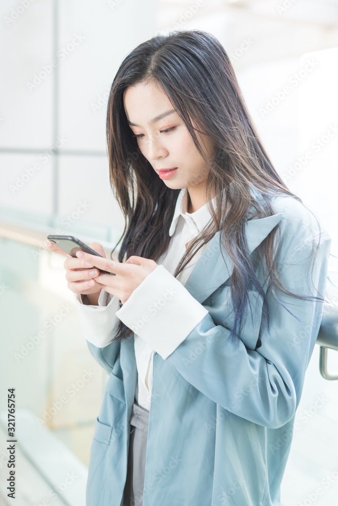 Business ladies use mobile phones in the corridor of office building Business ladies use mobile phones in the corridor of office building